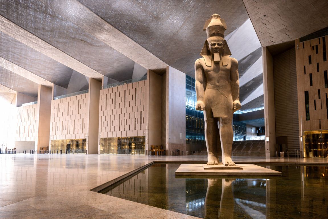 Colossal red granite statue of Ramesses II standing in the Grand Hall of the Grand Egyptian Museum