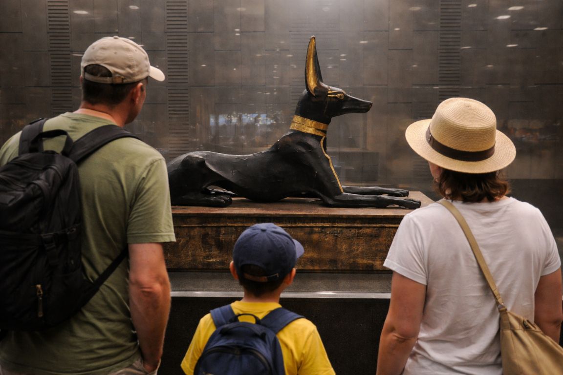 Family with child viewing Anubis statue inside the Grand Egyptian Museum during a tour with The Grand Egyptian Museum Tickets